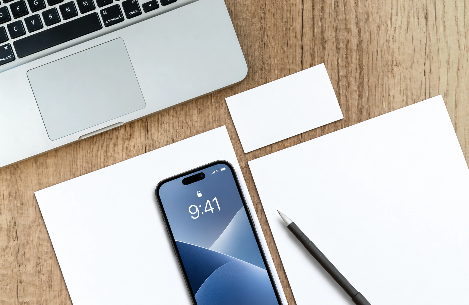 The same desk with a plain white business card, blank stationery, an unbranded laptop, and a generic phone lock screen